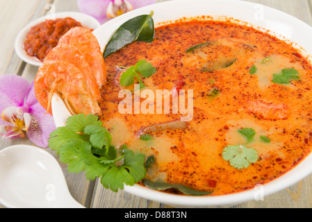 Tom Yum Nam Khon - Creamy Thai soup with prawns and mushrooms garnished with coriander and served with lime wedges. Stock Photo