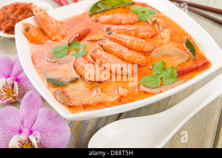 Tom Yum Nam Khon - Creamy Thai soup with prawns and mushrooms garnished with coriander and served with lime wedges. Stock Photo