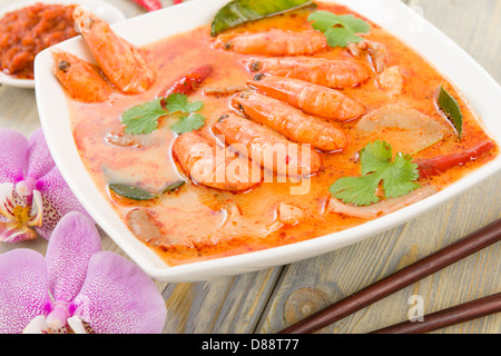 Tom Yum Nam Khon - Creamy Thai soup with prawns and mushrooms garnished with coriander and served with lime wedges. Stock Photo