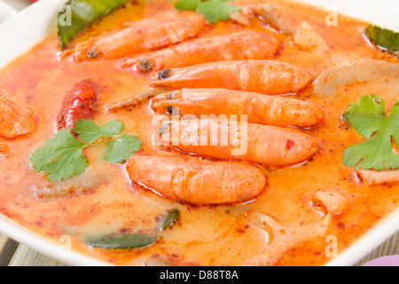 Tom Yum Nam Khon - Creamy Thai soup with prawns and mushrooms garnished with coriander and served with lime wedges. Stock Photo