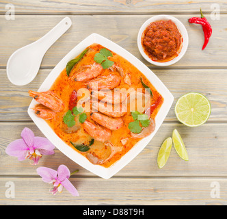 Tom Yum Nam Khon - Creamy Thai soup with prawns and mushrooms garnished with coriander and served with lime wedges. Stock Photo