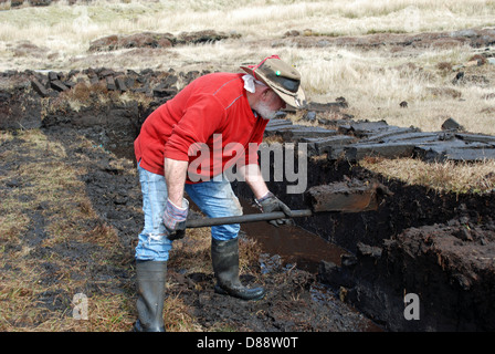 Man cutting turf in a peat bog on Aranmore island, in County Donegal. Stock Photo