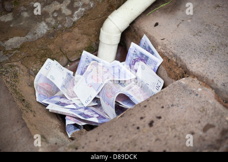 Throwing money down the drain. Stock Photo