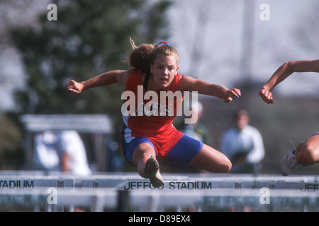 High School girl competing in track and field hurdles. Stock Photo