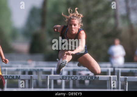 High School girl competing in track and field hurdles. Stock Photo