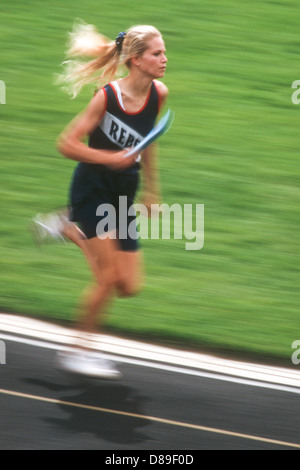 High School girl competing in track and field relay. Stock Photo