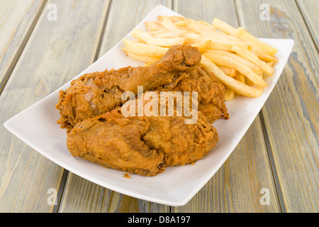 Fried Chicken & Chips - Chicken pieces on the bone coated in spicy flour and deep fried served with fries. Stock Photo