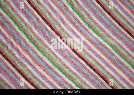 This image shows a fabric with diagonal stripes in salmon, blue, and green. The knit texture emphasizes the soft, stretchy material, making it suitable for various clothing items or textile applications. Stock Photo