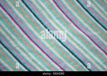 This fabric features a diagonal stripe pattern with alternating bands of teal, pink, and peach. The knit texture adds softness and flexibility, making it suitable for various clothing and textile applications. The color combination offers a vibrant yet harmonious aesthetic, with the stripes creating a dynamic visual effect. Stock Photo