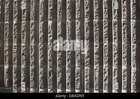 A concrete block wall featuring a fluted texture with vertical ridges. The design creates a unique, patterned surface, often used in construction for aesthetic or functional purposes. Stock Photo