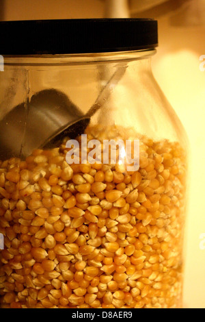 A jar filled with popcorn kernels, ready to be popped. Popcorn is a popular snack enjoyed worldwide, and kernels are typically stored in airtight containers to maintain freshness. Stock Photo