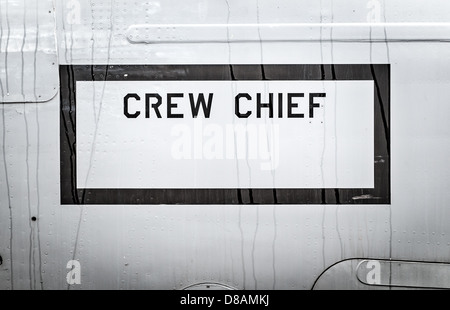 Big text Crew Chief in black frame written on side of airplane. Military aircraft close-up. Part of army air transport. Stock Photo