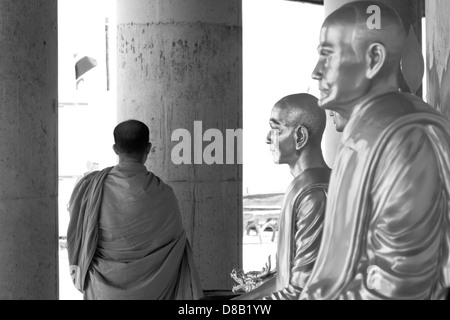 PHUKET, THAILAND FEBRUARY 15 2013: Buddhist monk walks by statues of Buddha at Big Buddha Monument Stock Photo