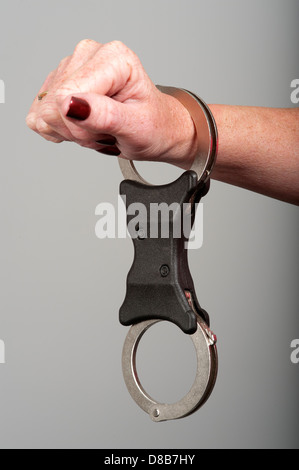 Locked in police issue handcuffs. Humane restraint cuffs made by Hiatts locked onto a woman's wrist Stock Photo