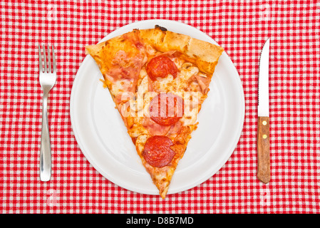 Pepperoni pizza slice on white plate served on table. Stock Photo