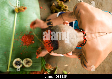 Young native of the ethnic group Tsachila mixes natural ingredients to paint the body of his fellow community Stock Photo