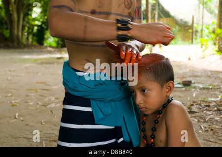 Young native of the ethnic group Tsachila paints the body of a child in the community Stock Photo