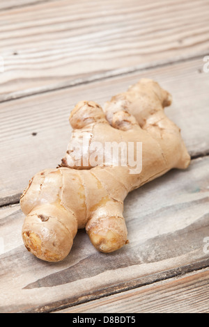 A whole fresh ginger root on a sanded wood surface. Stock Photo