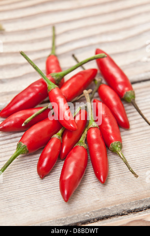 A pile of red Thai bullet chillis on a sanded wood surface. Stock Photo