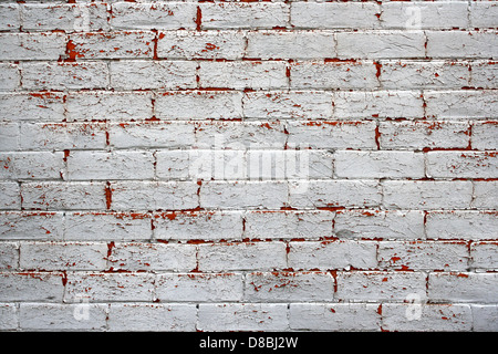 This image shows a brick wall with peeling paint, a result of aging and weathering. The peeling paint creates a distressed and textured surface, often associated with older buildings or rustic environments. Such walls are commonly found in urban areas, where age and exposure to the elements take their toll on building surfaces. Stock Photo
