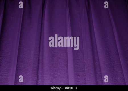 A close-up of purple curtains, showcasing the rich texture and smooth folds of the fabric. The light highlights the subtle sheen and depth of the material. Stock Photo