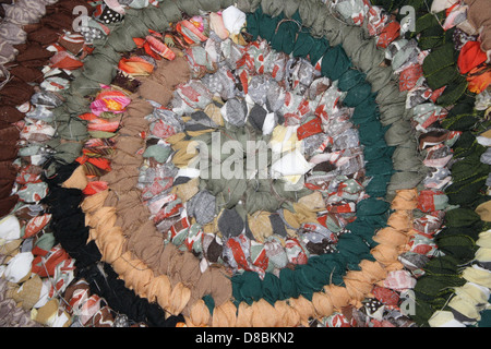 A close-up image showing the intricate texture of a rag rug. The woven fabric features various colors and patterns typical of traditional rag rugs, emphasizing the craftsmanship involved in its creation. Stock Photo
