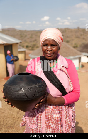 An african woman holding a traditional, handmade, clay pot. Stock Photo