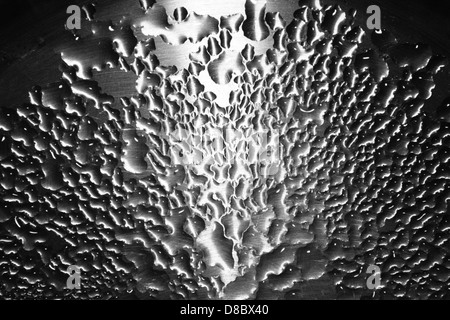 Water droplets are seen resting on a brushed steel surface, reflecting light. The metallic surface adds a sleek, modern touch, while the water droplets create a contrast that emphasizes the texture of the metal. Stock Photo