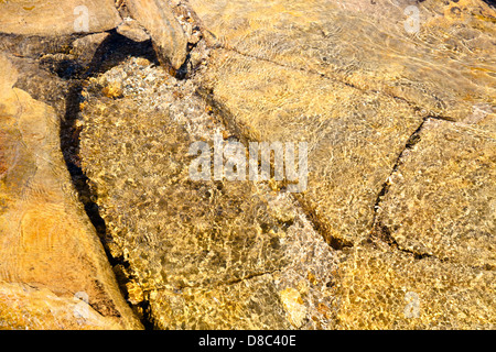 Abstract view of clear rippling stream water flowing over rock and stone with reflected sunlight, England, UK Stock Photo