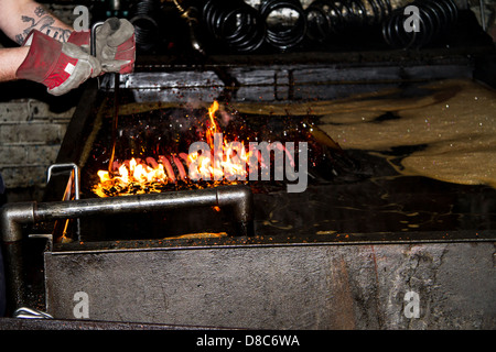 Coils suspension spring being lowered into oil quenching bath in a UK manufacturing company. Stock Photo