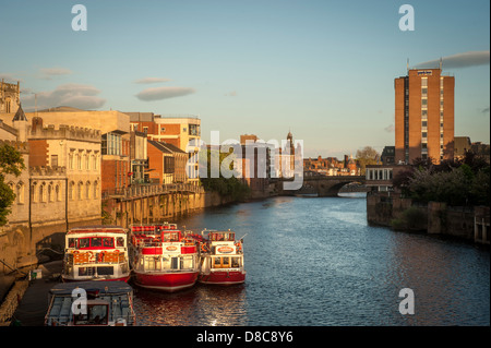 River Ouse on a sunny summer evening with moored cruise boats, and Ouse Bridge in the distance, York, UK. Stock Photo