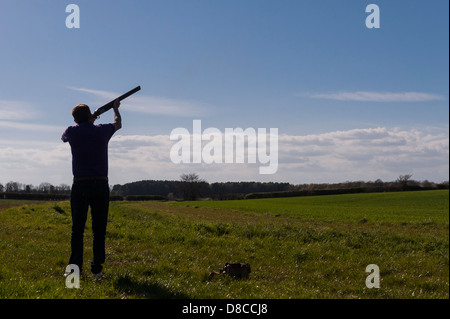 A silhouette of a man shooting clay pigeons with a shotgun in the Uk Stock Photo