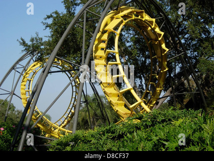 A yellow roller coaster track set amid trees. Stock Photo