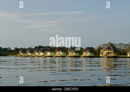 Thatch roofed bungalows on stilts in lagoon at Colon Island Stock Photo