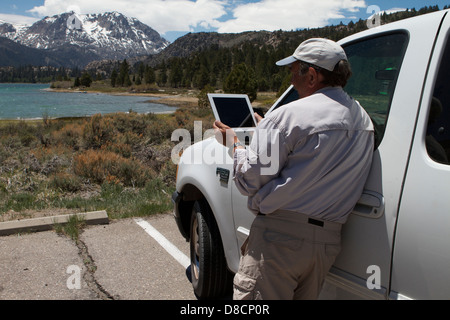 Tourist at June Lake in the Eastern Sierra Mountains of California reading information from an ipad Stock Photo