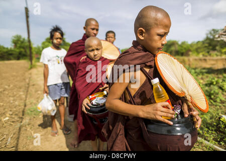 May 25, 2013 - Mae Sot, Tak, Thailand - Burmese novices on their morning alms rounds walk through the countryside in an unofficial village of Burmese refugees north of Mae Sot, Thailand. Their community is about 50 metres from the Burmese border with Thailand. About 200 people live in thatched huts spread throughout the community. They're close enough to Mae Sot that some can work in town and Burmese merchants from Mae Sot come out to their village to do business with them. The Burmese in the village don't residency papers for Thailand and are technically considered illegal immigrants. Fifty y Stock Photo