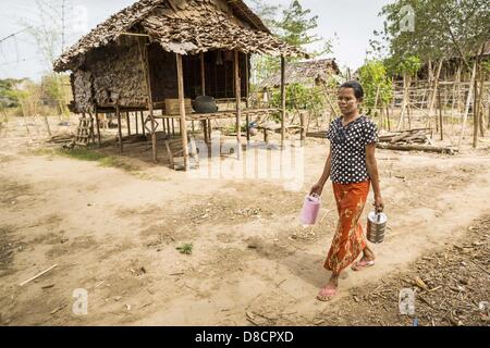 May 25, 2013 - Mae Sot, Tak, Thailand - A Burmese woman walks through an unofficial village of Burmese refugees north of Mae Sot, Thailand. Their community is about 50 metres from the Burmese border with Thailand. About 200 people live in thatched huts spread throughout the community. They're close enough to Mae Sot that some can work in town and Burmese merchants from Mae Sot come out to their village to do business with them. The Burmese in the village don't residency papers for Thailand and are technically considered illegal immigrants. Fifty years of political turmoil in Burma (Myanmar) ha Stock Photo