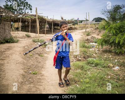 May 25, 2013 - Mae Sot, Tak, Thailand - A Burmese boy chews on sugarcane as he walks through an unofficial village of Burmese refugees north of Mae Sot, Thailand. Their community is about 50 metres from the Burmese border with Thailand. About 200 people live in thatched huts spread throughout the community. They're close enough to Mae Sot that some can work in town and Burmese merchants from Mae Sot come out to their village to do business with them. The Burmese in the village don't residency papers for Thailand and are technically considered illegal immigrants. Fifty years of political turmoi Stock Photo