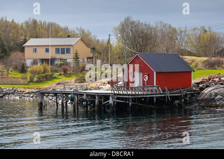 Traditional Norwegian red wooden fishing boat barn on the sea coast in spring Stock Photo