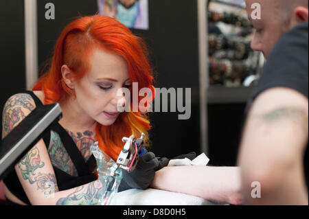 US model and tattooist, Megan Massacre from New York, works on a male at the Great British Tattoo Show, London, UK. Stock Photo
