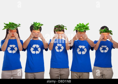 Group of people holding plants, obscuring faces, studio shot Stock Photo