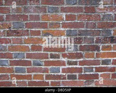 A red stone wall constructed with natural stones shows intricate patterns and textures. The rich red color and strong structure are characteristic of stone masonry used in various architectural projects. Stock Photo