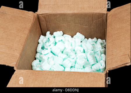 Cardboard box filled with styrofoam shipping peanuts isolated on black background Stock Photo