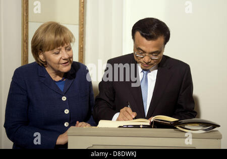 Berlin, Germany. 26th May, 2013. German Chancellor Angela Merkel (L) watches China's prime minister Li Keqiang (R) sign the guest book on his arrival for a dinner at the German government's Meseberg Palace in Meseberg some 60 km north of Berlin on May 26, 2013. China's Premier Li Keqiang met German Chancellor Angela Merkel as the close economic partners seek to weather a brewing trade spat between Beijing and the EU and forge deeper ties. Photo: Odd Andersen dpa/Alamy Live News Stock Photo