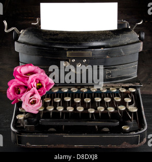Old antique black vintage typewriter and empty paper for copy space, with red romantic flowers Stock Photo