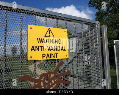 Yellow Warning Anti-Vandal paint sign on a playground gate , Grappenhall  Warrington  Cheshire England UK Stock Photo