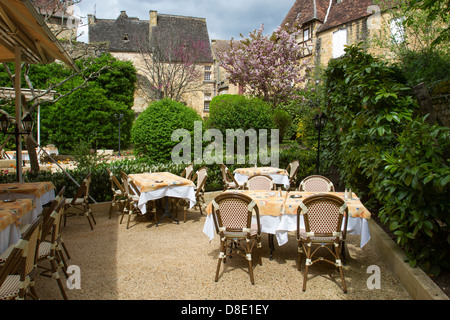 Outdoor courtyard dining at a restaurant by medieval sandstone buildings in charming Sarlat, Dordogne region of France Stock Photo