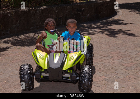 Little African American boy and girl riding an electrical go-cart, Finley Park, Santa Rosa, California, USA, North America Stock Photo