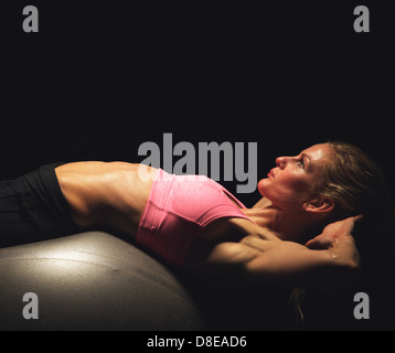 Closeup of a woman focused on exercising using a fitness ball Stock Photo