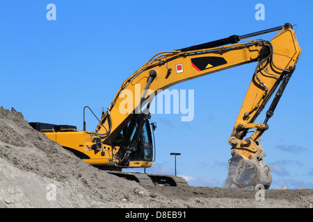 Yellow excavator on the blue sky background Stock Photo